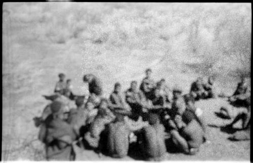 Group of seated Ju/'hoansi and Lorna Marshall (out of focus)