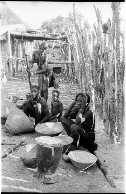 Four Hinga women working on grain; one woman is pounding in a mortar