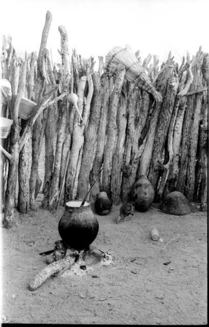 Pot on a fire in a Hinga kraal and baskets hanging from a fence in the background