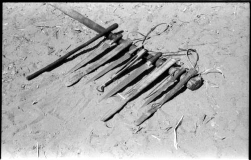 Four knives, their wooden sheaths, and a stick, all lying on a pestle