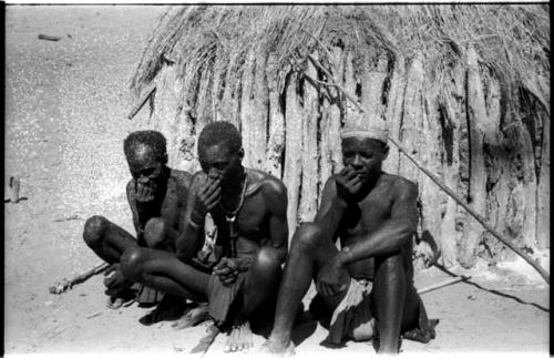 Three men sitting and taking snuff