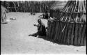 Two men seated by huts