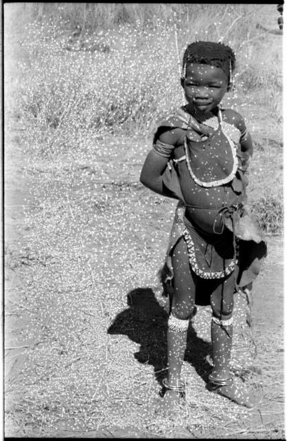 "Little N!ai," standing, and wearing a leather apron around her neck and waist