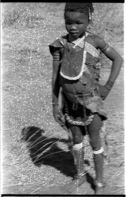 "Little N!ai," standing, and wearing a leather apron around her neck and waist