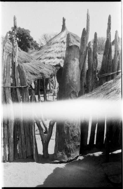 Wood pole fence and huts in the background (light struck)