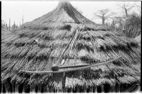 Bow, knobkerrie, arrows, and spear displayed on a thatched roof