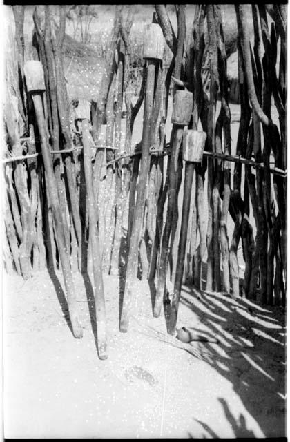 Pestles for pounding grain leaning against a fence