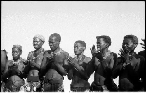 Women standing in a semi-circle, clapping for a dance