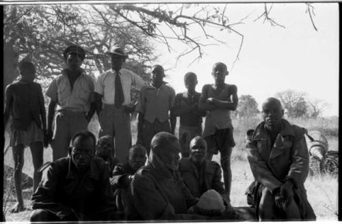 Group of men sitting and standing, all wearing Western clothing