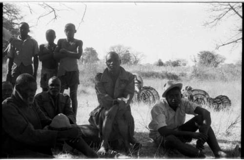 Group of men standing and sitting, all wearing Western clothing