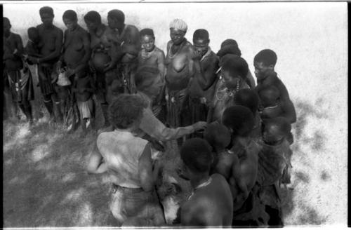 Lorna Marshall and Elizabeth Marshall Thomas talking to a group of women and children and giving them tobacco