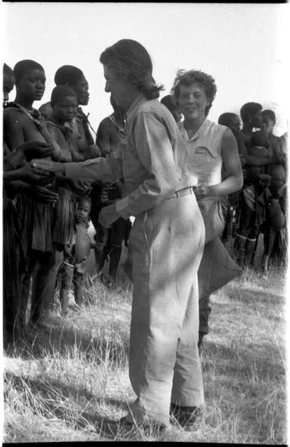 Lorna Marshall and Elizabeth Marshall Thomas talking to a group of women and children and giving them tobacco