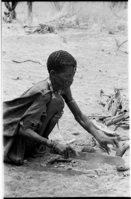 "Old Xama" pounding a piece of animal skin with a fire paddle