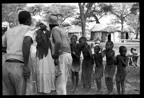 Judas Kangengi and Ananias singing in front of a line of women and boys clapping