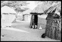 Woman lying in the doorway of a hut, seen from a distance