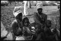 Two women seated, child sitting in one woman's lap, two children sitting in front of them