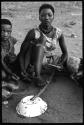 Young woman sitting in a group, playing a dandiri