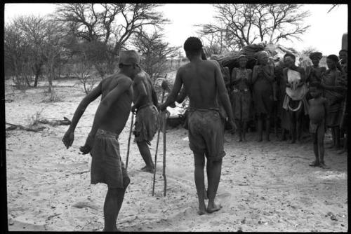 Group of men dancing, people standing on the side