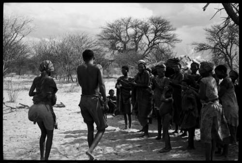 N/kxabe and Tama, seen from behind, next to a group of women clapping