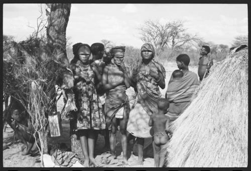 Dadum and N/Kxabe standing with a group of people under a tree