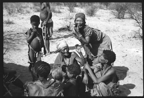 "Old Nǂam" with a group of people sitting, /Gaishay standing in the background