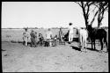 Expedition members standing by a water trough; man with two horses