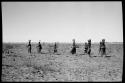 Group of women walking in a line, carrying buckets on top of their heads