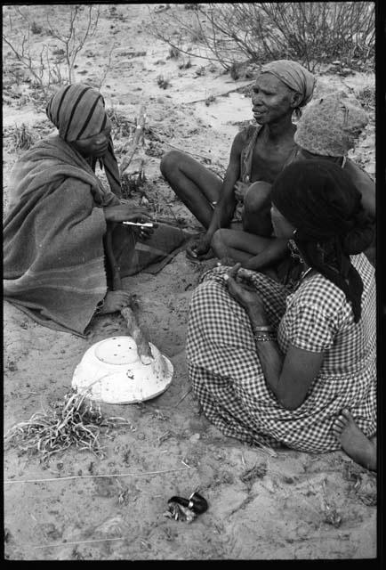 N/kxabe; Tomku; Dadum; and ǂKxoba sitting and playing a dandiri