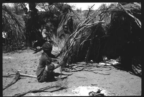 "Old Sãõ?//e" placing sticks in ground for her skerm extension