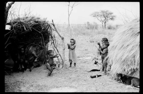 Children dancing between two skerms; three people in one skerm sitting and watching