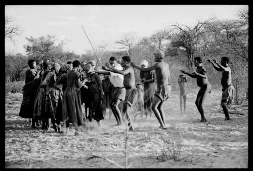 Group of men approaching group of women who are singing and clapping