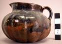 Ceramic pitcher, flat base, fluted sides, constricted neck, spouted lip