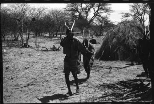 Two men performing the Eland Dance, holding wooden horns up to their heads
