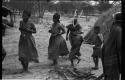 Group of people performing the Eland Dance; a line of people, men holding wooden horns to their heads
