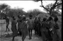 Group of people performing the Eland Dance; group of women clapping; men with wooden horns on their heads