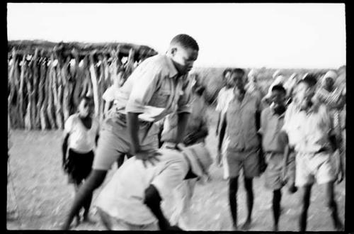 Boy leaping over another boy, people watching in the school yard (out of focus)