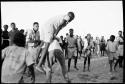 Boy leaping over another boy, people watching in the school yard