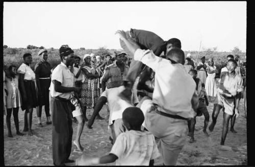 Boy leaping on another boy's back, people watching in the school yard