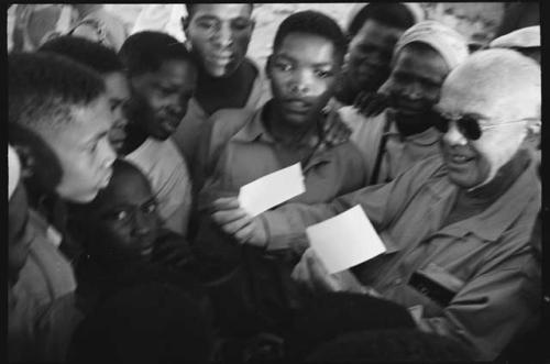 Laurence Marshall showing polaroid photographs to a group of people, close-up view