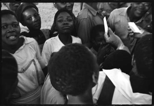 Laurence Marshall showing polaroid photographs to a group of people, close-up view