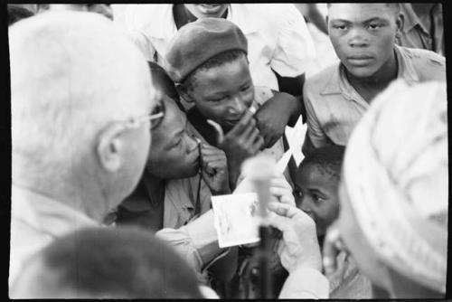 Laurence Marshall showing polaroid photographs to a group of people, close-up view