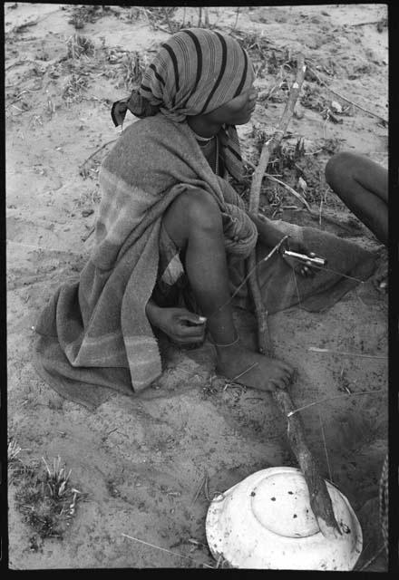 Woman sitting and playing a dandiri, seen from behind
