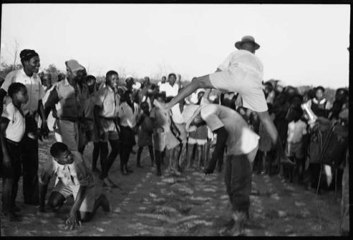 School boys playing a game; a group watching from the side