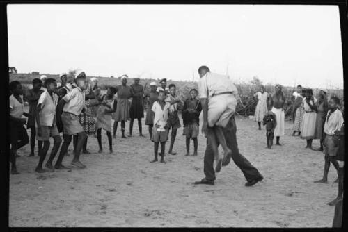 School boys playing a game; a group watching from the side