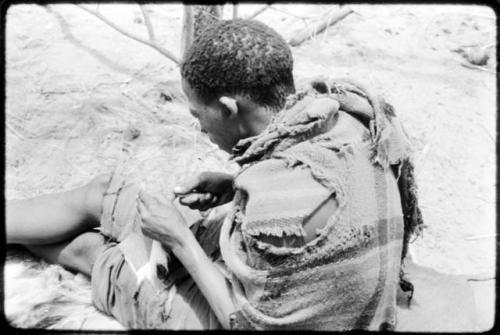 Tama sewing, showing how he makes a hole with an awl for the thread to go through, close-up (copy of color slide 2001.29.8361)