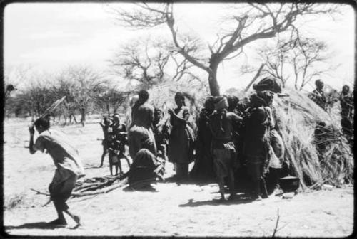 Women performing the Eland Dance, with some standing in front of a skerm, singing and clapping, and others dancing around the skerm (copy of color slide 2001.29.8649)