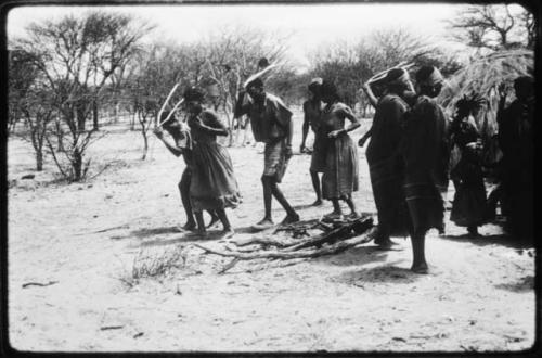 Men performing the Eland Dance, holding horns to their heads and coming around from behind the skerm (copy of color slide 2001.29.8671)