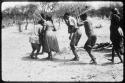 Group of people performing the Eland Dance, with Twi cutting in between ≠Kxoba and the man in front of her (copy of color slide 2001.29.8673)