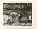 Churns under a thatched roof (print is a cropped image)