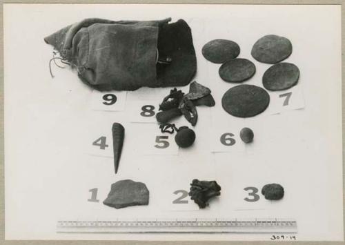 Possessions, including a carrying bag, oracle disks, and duiker horn, with a ruler for measurement (print is a cropped image)